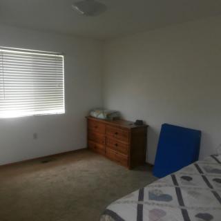 A simple bedroom with a dresser, bed, and window with blinds.