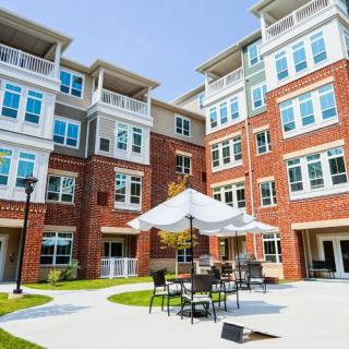 A modern apartment building with outdoor seating area on a sunny day.
