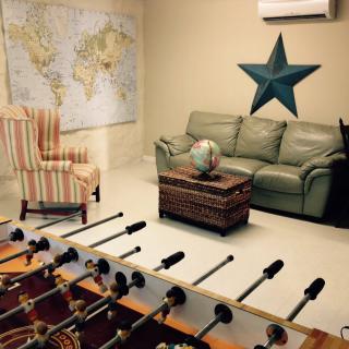 A cozy game room featuring a foosball table, comfortable seating, and world-themed decor.