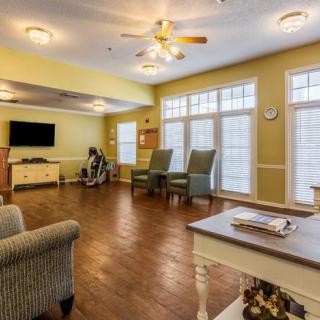 A cozy living room with large windows, comfortable seating, and a television for relaxation.