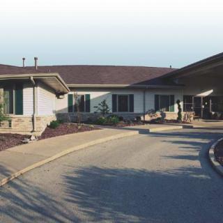 A one-story building with a sloped roof and a circular driveway.