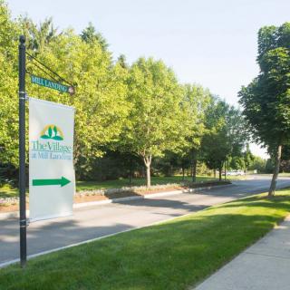 The entrance to a park with lush greenery and clear signage by the roadside.