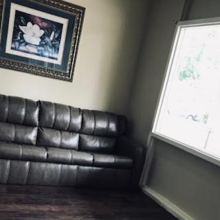 A cozy living room featuring a leather couch and a piece of artwork on the wall next to a window.