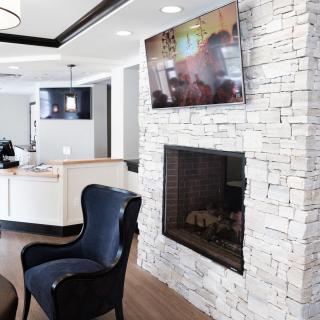 A modern living room with a stone fireplace, television, and elegant armchair.