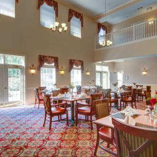 A spacious dining room with neatly arranged tables and chairs, featuring large windows and elegant decor.