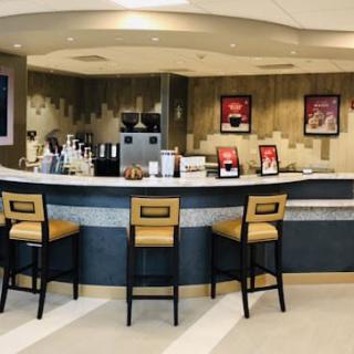 A modern cafe counter with bar stools and a selection of coffee equipment.