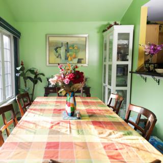 A colorful dining room with a table covered by a checkered cloth, surrounded by wooden chairs and adorned with a vase of flowers.