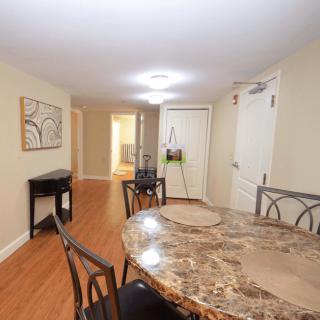 A modern dining room with a marble table and hardwood floors.
