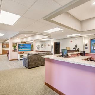 A spacious and well-lit office reception area with pink accents and comfortable seating.