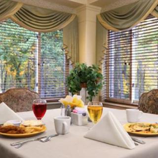 A beautifully set dining table with plates and drinks by large windows adorned with elegant curtains.