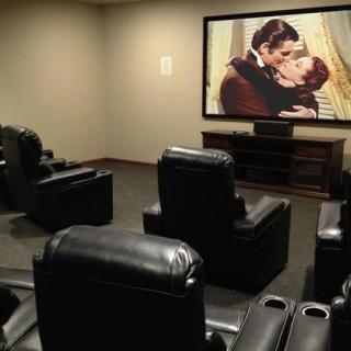 A home theater setup with a large projection screen and comfortable leather seating.
