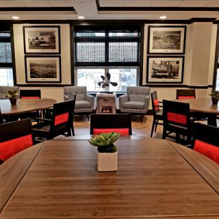 A modern dining area with wooden tables, red-accented chairs, and elegant decor.