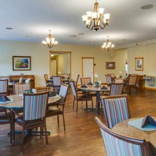 A well-decorated dining room with multiple tables and chairs, elegant lighting, and a wooden floor.