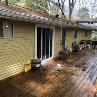 A wooden deck attached to a house with sliding glass doors and outdoor seating.