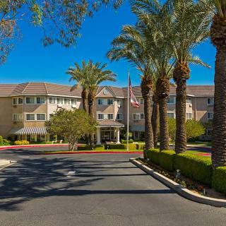 A residential building surrounded by palm trees on a sunny day.
