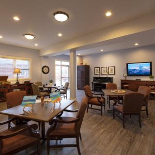 A cozy lounge area with tables, chairs, a television, and a fireplace.