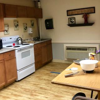 A spacious kitchen featuring wooden cabinetry, a dining table, and essential appliances for cooking.
