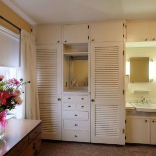 A cozy bedroom with a built-in wardrobe and a bouquet of flowers on the dresser.