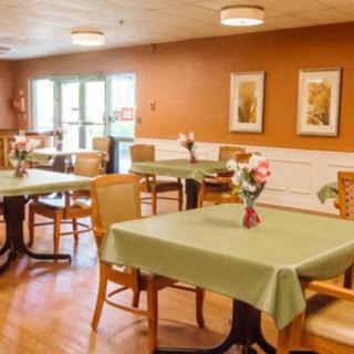 An inviting dining room with tables covered in green tablecloths and decorated with floral centerpieces.
