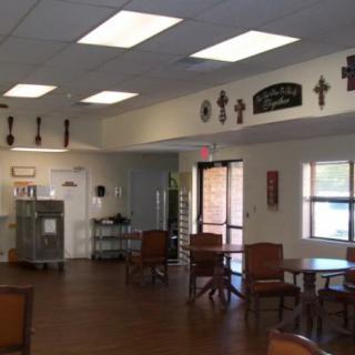 An empty dining area with several tables and chairs, adorned with wall decorations including crosses.