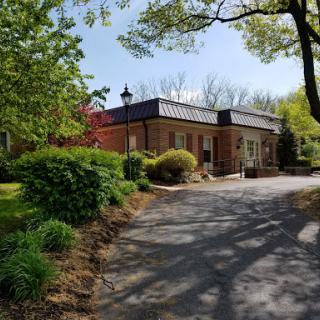 A serene view of a brick building surrounded by lush greenery and trees.