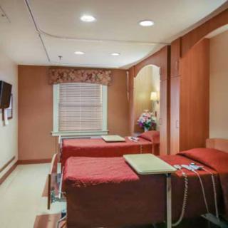 A cozy hospital patient room equipped with two beds and a warm color scheme.