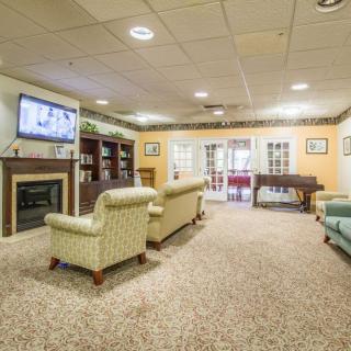 A cozy living room featuring comfortable seating, a TV, bookshelves, and a fireplace.