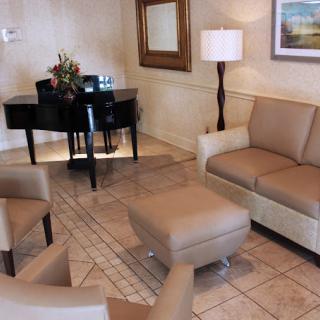 A cozy living room with a piano, sofas, and a lamp creating a welcoming atmosphere.