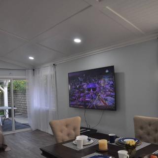 A modern living room with a wall-mounted television and dining area.