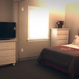 A cozy bedroom featuring a bed, dresser, and television.