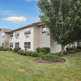 A residential apartment building with well-maintained landscaping and greenery under a partly cloudy sky.