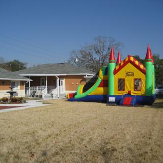 A colorful inflatable bounce house set up on a lawn in front of a residential home.