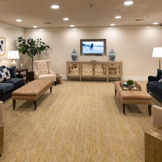 A spacious living room with elegant furnishings, including sofas, benches, lamps, and decorative elements.