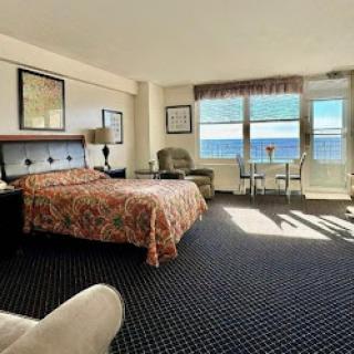 A cozy hotel room with an ocean view, featuring a comfortable bed and ample natural light.