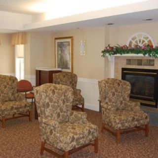 A cozy living room with patterned chairs arranged around a fireplace.