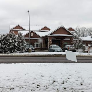 A snowy scene featuring a building with a cloudy sky overhead.