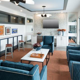 A modern living room featuring cozy blue chairs, a wall-mounted TV, and contemporary artwork.