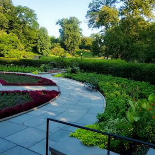 A serene garden pathway winding through lush greenery and colorful flower beds.