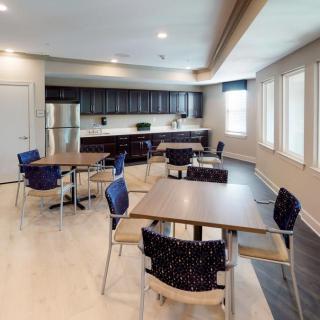 A modern kitchen and dining area with tables and chairs, featuring large windows.