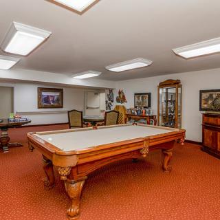 A spacious recreation room featuring a billiards table and classic interior decor.