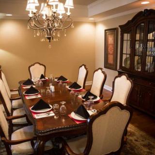 An elegant dining room with a chandelier and formal place settings.