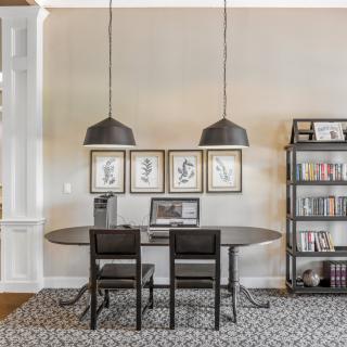 A modern home office setup with a sleek desk, pendant lighting, and minimalist decor.