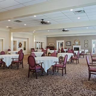 An elegant dining room setup with multiple tables and chairs on a carpeted floor.