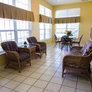 A bright sunroom with wicker furniture and large windows.
