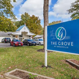 Exterior view of The Grove facility with a clear sign and surrounding landscape.
