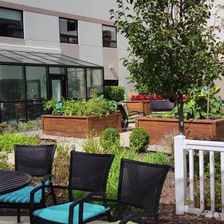 A serene outdoor garden area with raised planters and patio seating outside a building.
