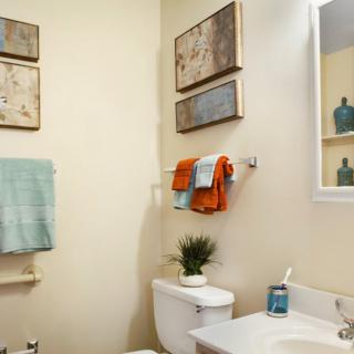 A neatly organized bathroom with colorful towels and decorative wall art.