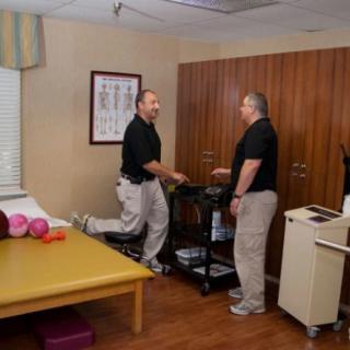 Two individuals engaging in a physical therapy session in a clinic setting.