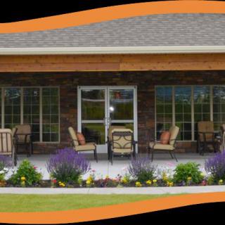 A cozy patio with comfortable seating and vibrant flowers in front of a building.