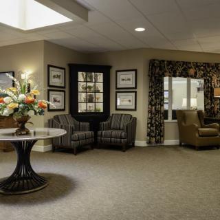 A well-decorated lobby area featuring comfortable seating, framed artwork, and a centerpiece table with a floral arrangement.